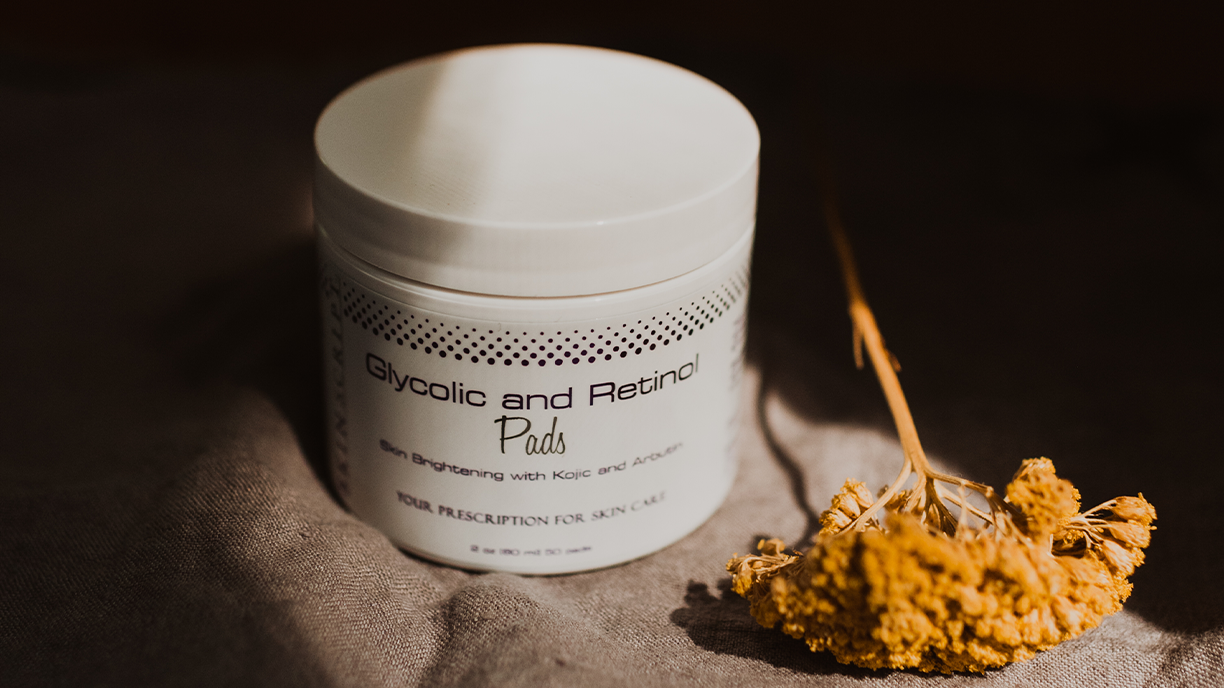 Glycolic and Retinol Pads in dramatic lighting next to a dried flower.